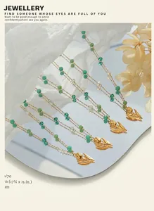 Artistic close-up of gold tulip pendant with green crystal beads on a mirror surface