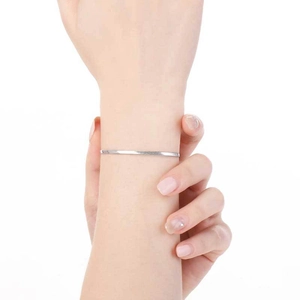 Détail d'un bracelet chaîne serpent plate en argent porté au poignet sur fond blanc