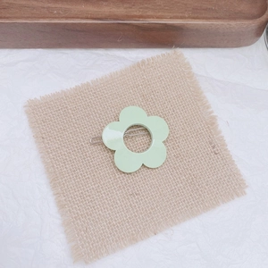 Detail of mint green flower hair clip on beige linen cloth with a natural wood background
