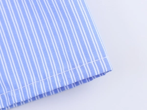 Dettaglio macro del tessuto in cotone a righe blu e bianche con finiture di cucitura