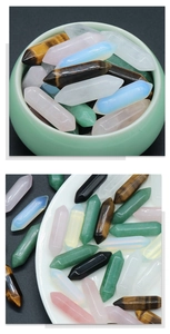 Polished hexagonal natural crystal prisms in various colors displayed in a green ceramic bowl