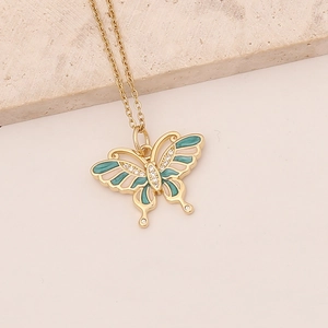 Gold butterfly necklace with turquoise enamel and zircon stones on a beige background