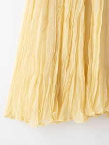 Detailed close-up showing the textured pleated yellow chiffon fabric of the long skirt