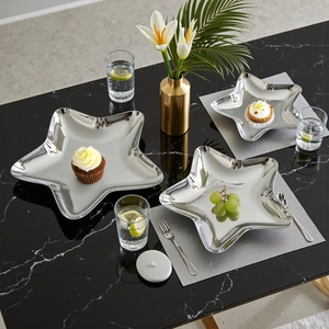 Minimalist silver star-shaped metal serving trays in three sizes on a black marble table