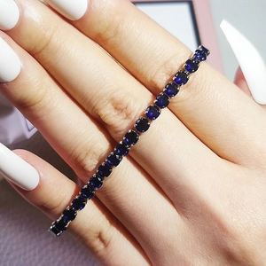 Detail of dark blue round-cut zircon tennis bracelet worn on wrist with silver setting