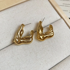 Detailed view of gold irregular lava-style earrings resting on a beige linen jewelry box