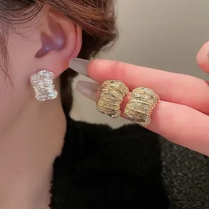 Minimalist textured metal stud earrings in gold and silver finishes for a retro look
