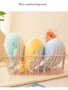 Detailed view of plush whale keychains in mint green, yellow and blue in a wire basket