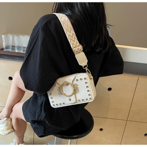 Detailansicht einer weißen Vintage-Tasche mit goldenen Nieten und Retro-Reliefschließe