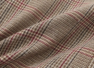 Close-up of thick glen plaid tweed fabric with brown, beige, and red stripe patterns