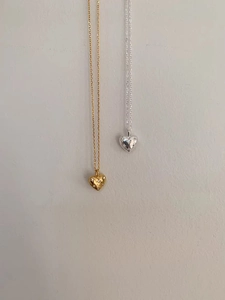 Macro detail of gold and silver heart pendants with sparkling starburst stone setting