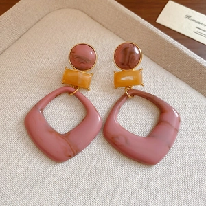 Detail of resin geometric earrings with marble texture, amber and pink earthy tones