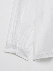Gros plan du poignet à volants blancs et du bouton sur une chemise en lin à manches longues