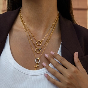 Detail of layered gold and silver mixed color cross necklace with ring pendant on model