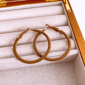Detailed view of round brown flocked earrings placed in a premium jewelry display box