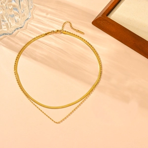 Detail of gold double-layer necklace set with flat snake chain and delicate bead link