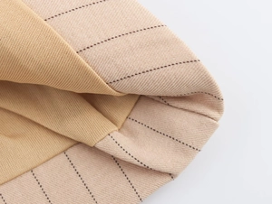 Gros plan sur le tissu rayé beige et la doublure en tricot camel doux de la tenue