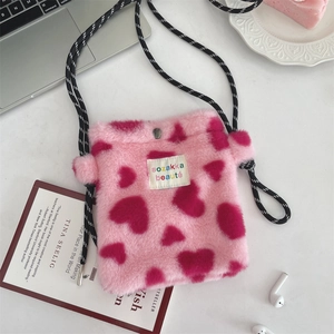 Detail of pink plush heart bag with woven strap and snap button closure