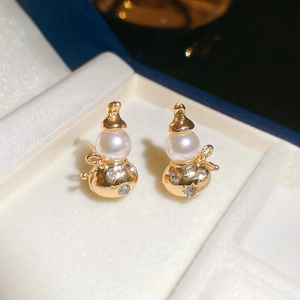 Detailed close-up of golden gourd earrings with white pearls and sparkling zircon accents