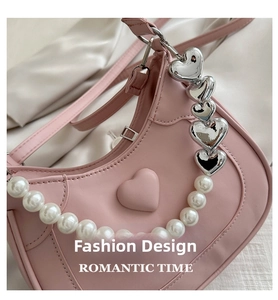 Detailed shot of pink heart-shaped bag with pearl handle and silver romantic charms