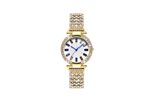 Vue macro d'une montre dorée avec index pierres colorées et lunette sertie de strass