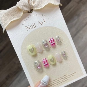 Handmade short press-on nails with yellow and pink heart patterns on bow display card