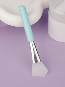 Detail of flat silicone facial mask brush with light blue handle and silver metal ferrule