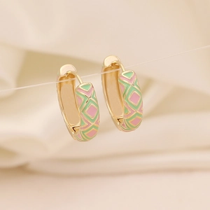 Détail macro de créoles géométriques dorées avec motifs à damier en émail rose et vert