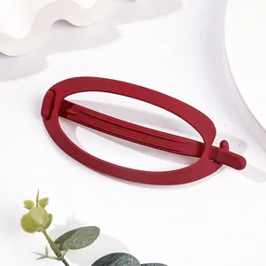 Detail of a matte red oval hair claw clip for women featuring a minimalist hollow design