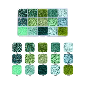 Macro view of 15 compartments showing diverse green and teal glass beads for DIY jewelry