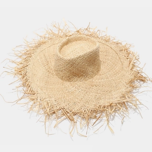 Detailed top view of a wide brim raffia sun hat featuring raw fringe edges and straw weave