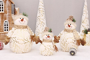 Three plush Christmas snowmen in white and gold festive outfits on holiday background