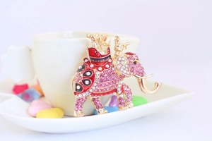 Detail of pink rhinestone elephant keychain with gold metal finish on white cup edge