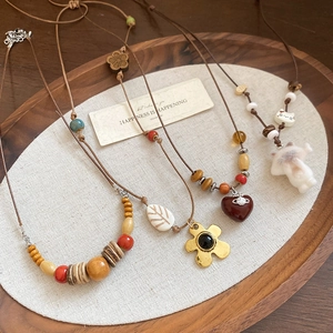 Détails du collier bohème avec perles en bois et pendentifs fleurs sur un plateau en bois