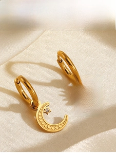 Macro shot of gold sun and moon hoop earrings with crystal on elegant silk fabric