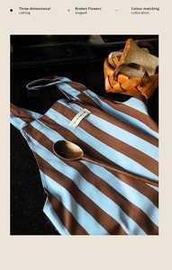 Detail of blue striped kitchen apron with Be Original label on black marble countertop