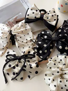 Detail of silk polka dot bow hair claw and scrunchies in black and white pattern