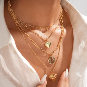 Golden multi-layer necklace with heart and world map pendants on a white shirt