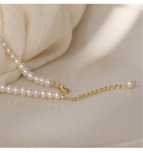 Detail of elegant pearl necklace showing golden lobster clasp and adjustable chain