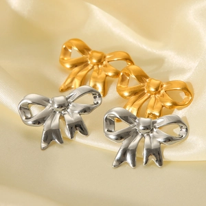 Elegant 18K gold and silver stainless steel bow earrings on a soft yellow satin background