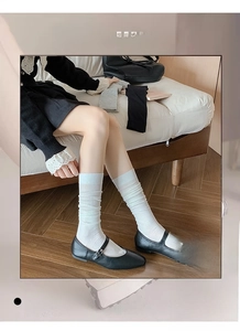 Detail of white ribbed slouch socks with high elasticity and soft texture on model