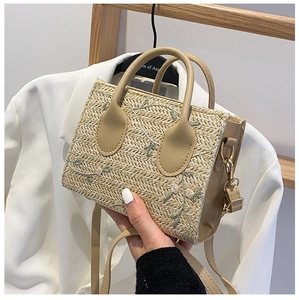 Detail of floral embroidery on a natural straw tote bag with brown PU leather handle