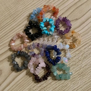 Detail of assorted natural raw crystal elastic rings stacked on a light wooden table