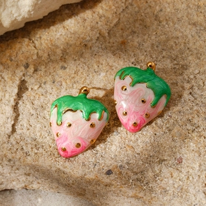 Close-up of strawberry enamel earrings with pink gradient texture on stone surface