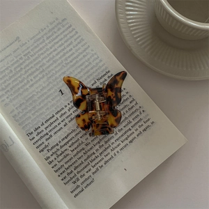 Detail of a butterfly hair claw clip with tortoiseshell pattern on an open book