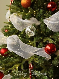 Close-up of white mesh Christmas tree ribbon with gold glitter edges and festive ornaments