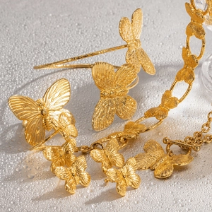 Vintage golden butterfly jewelry set featuring bracelet and earrings on water drop surface