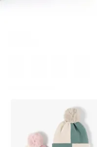 Detail of knit beanie texture showing pom-pom and warm dual-color striped wool fabric