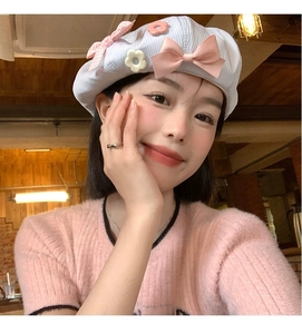Detailed texture of baby blue corduroy beret with pink bow and 3D floral accents