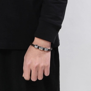 Detailed close-up of a men's black braided leather bracelet with stainless steel beads